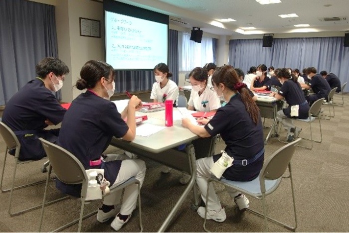 テーブルが4つ、それぞれに5名ずつ程度座り、向かい合ってこれまでの振り返りをしているようす